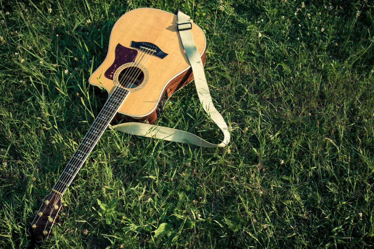 acoustic guitar with strap in the grass