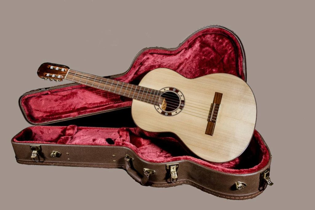 acoutic guitar sits in a red velvet lined case