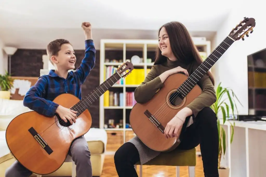 brother and sister playing guitar at home