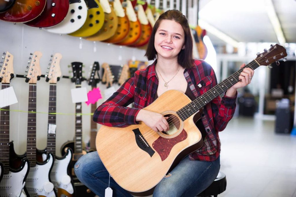 girl examining various acoustic guitars