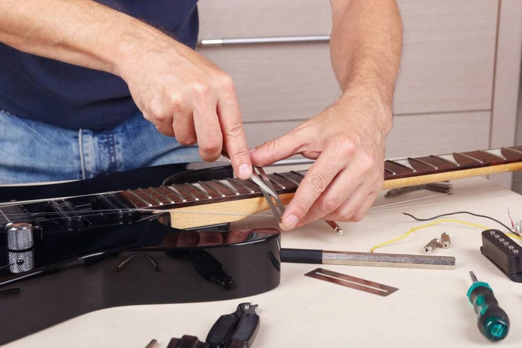guitar technician burnishes the edge of frets