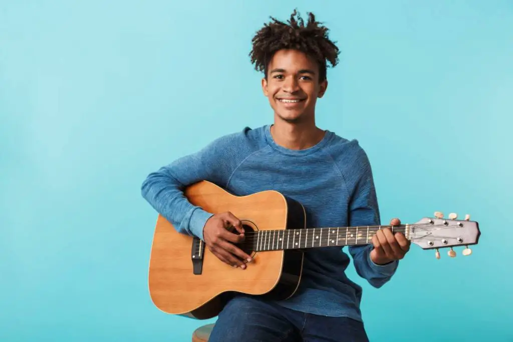 man playing a guitar while sitting