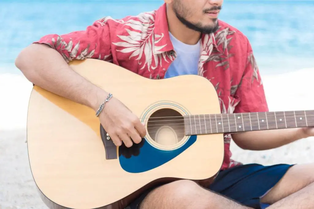 man playing acoustic guitar at the beach
