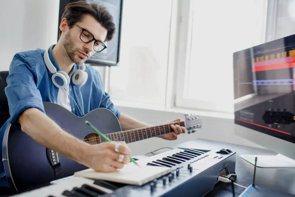 man plays guitar and produce electronic soundtrack