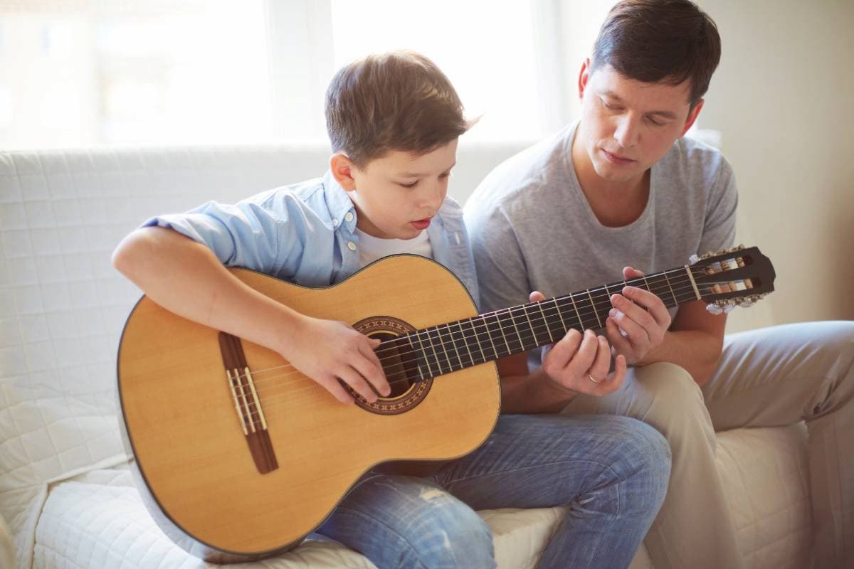 man teaching his son how to play the guitar