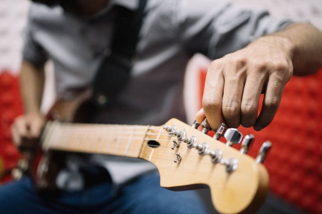 musician tuning guitar in music studio
