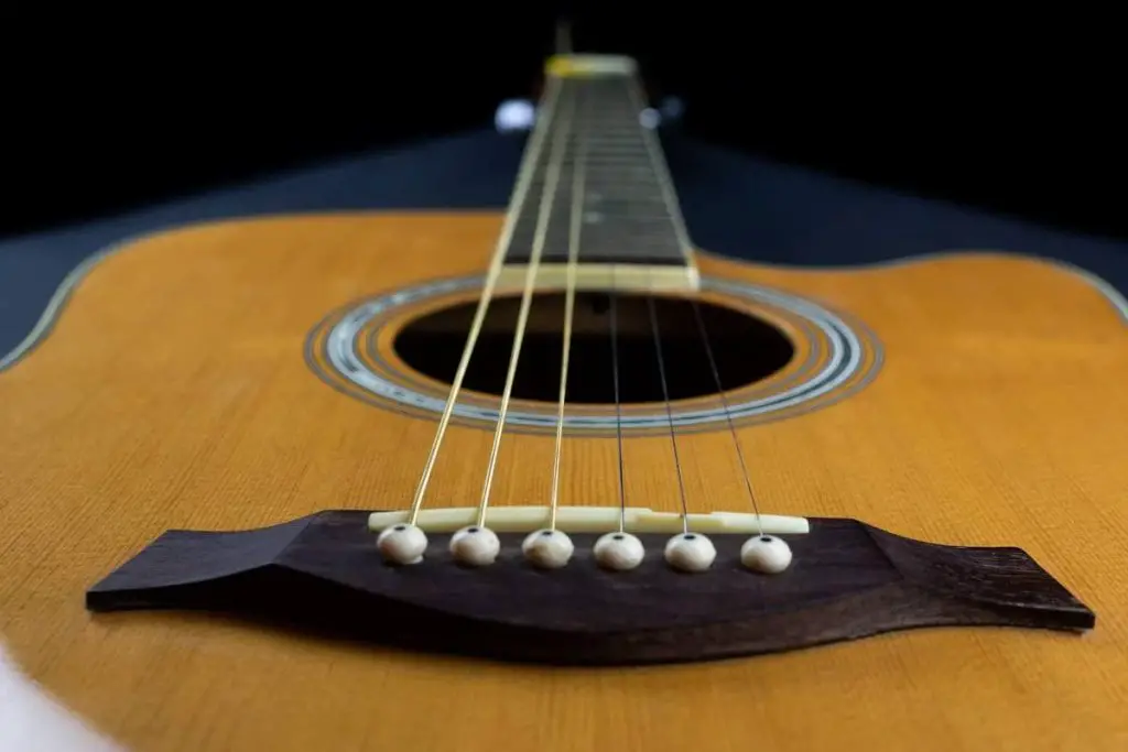 yellow guitar pick tucked into gold acoustic guitar