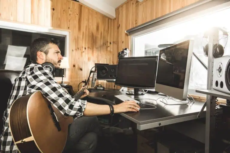 Musician recording in a home studio with a computer running the best free DAW