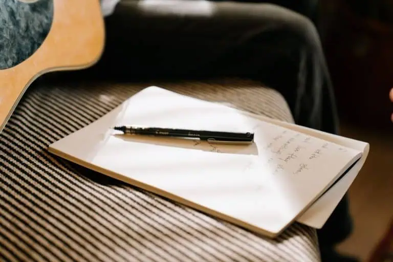 Notebook and pen for taking notes on an EQ frequency chart while mixing