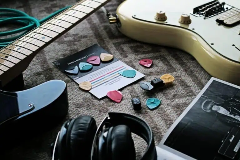 Headphones and guitar picks on a table for listening closely with an AI music detector