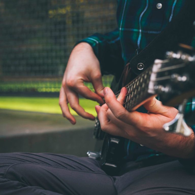 Bass guitar for beginners: player fingering the strings of an electric bass