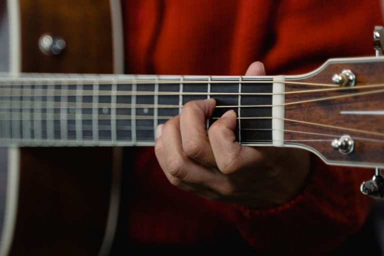 Hand playing an open chord to learn guitar keys for beginners