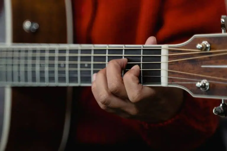 Hand playing an open chord to learn guitar keys for beginners