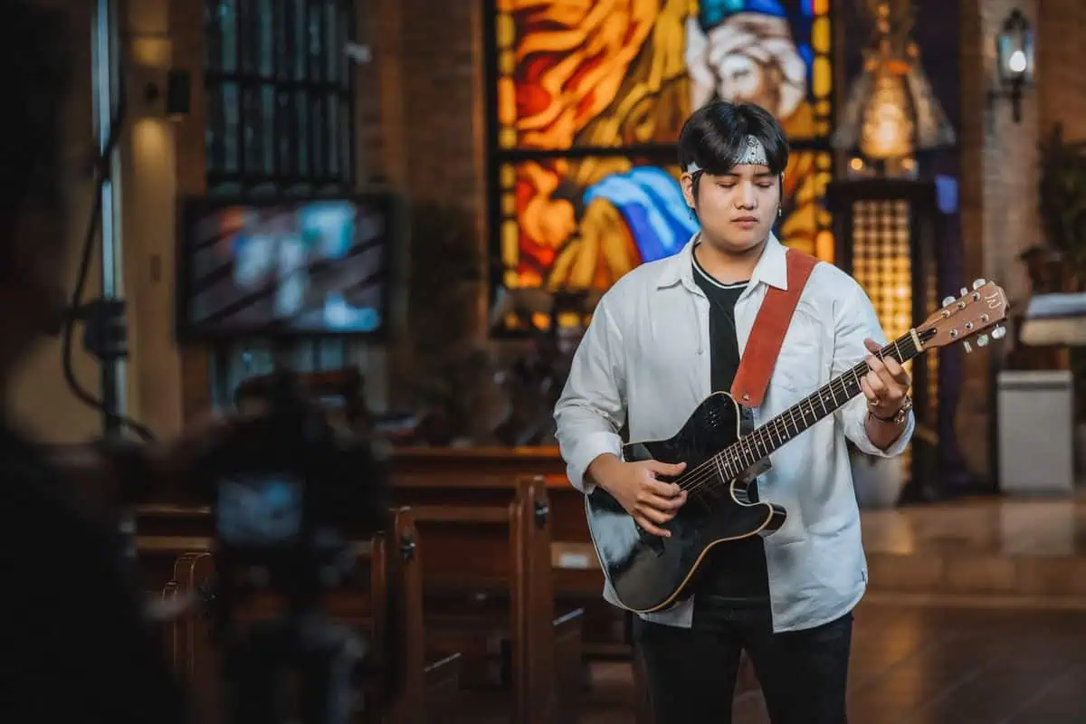 How to Rewrite a Hymn 2026: Retuned Hymns & Public Domain Hymns 2 Guitarist playing a hymn in a church, showing how to rewrite a hymn for modern worship