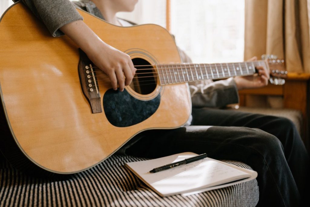 Christian Songwriting Prompts 2026: 40 Ideas for Your Next Worship Song 1 Songwriting prompts: songwriter with a guitar writing song ideas in a notebook