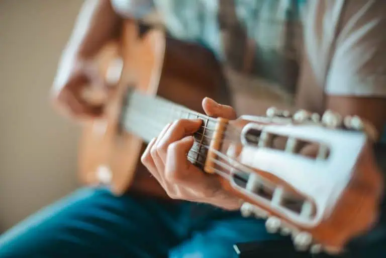 Person playing an acoustic guitar, learning hymns on guitar with easy chords