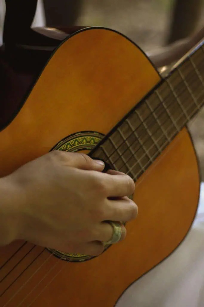 How to Write a Sad Song: Chords, Lyrics & Melody Tips 1 How to write a sad song: hand playing a quiet fingerstyle guitar part