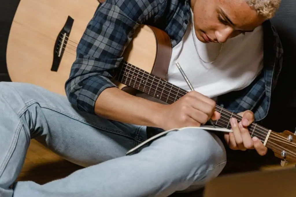 Christian Songwriting Contests, Camps & Conferences 2026 1 Rhyme schemes for songwriters: songwriter writing lyrics in a notebook with an acoustic guitar