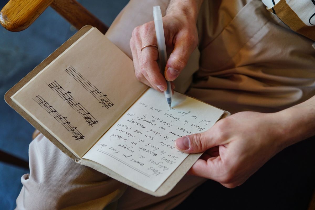 Songwriter writing lyrics in a notebook using Bible verses about music as inspiration